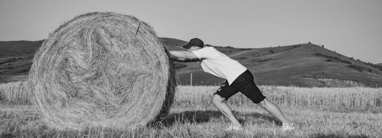 Man pushing hay bale