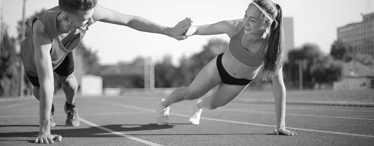 Two athletes high-fiving on the starting line of a running track
