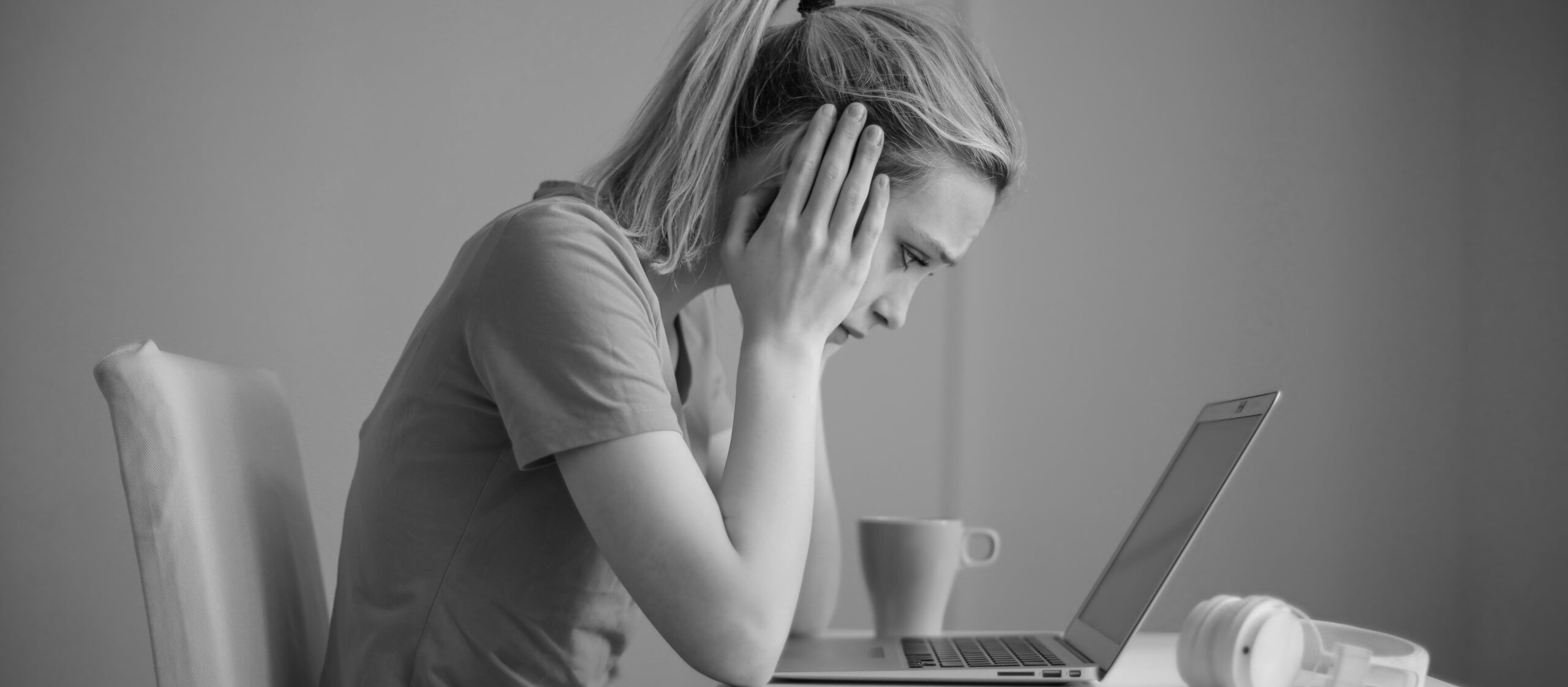 Frustrated and worried woman looking at a laptop with hands on her face