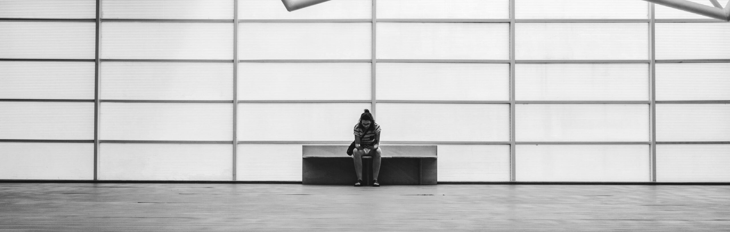 A person sits on a bench in an empty room