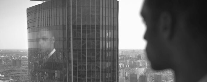 Reflection of a man looking out the window of his high-rise office building