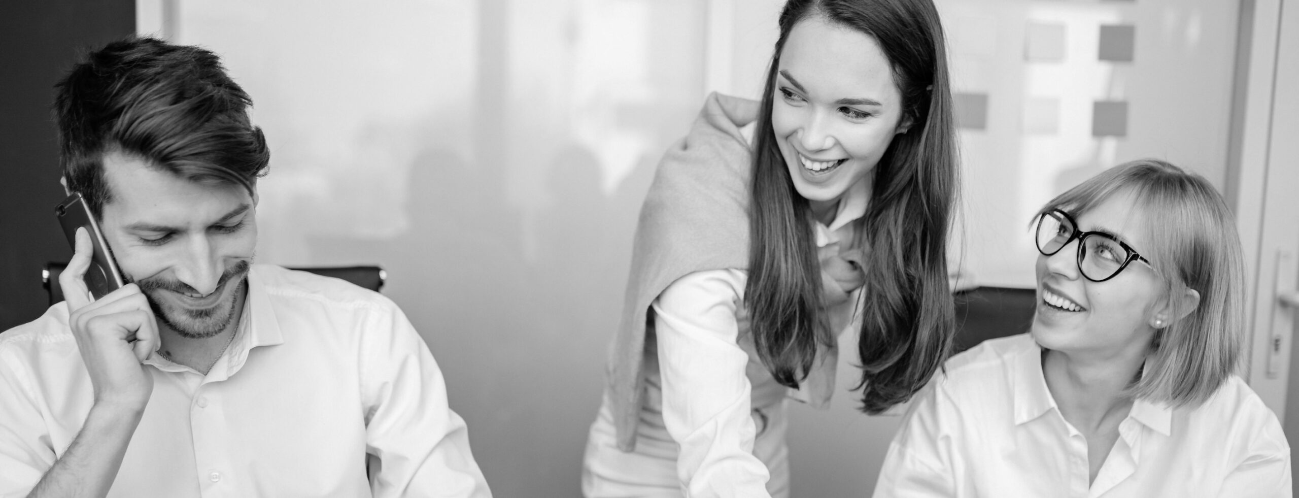 Work colleagues leaning on a desk and laughing